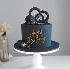 a black and gold birthday cake with wheels on top