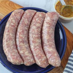 four slices of sausage on a blue plate next to a bowl of mustard and seasoning