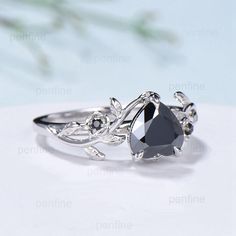 a black diamond ring sitting on top of a white table next to a flower arrangement