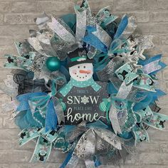 a snowman wreath on a brick wall with blue and silver ribbon around the top