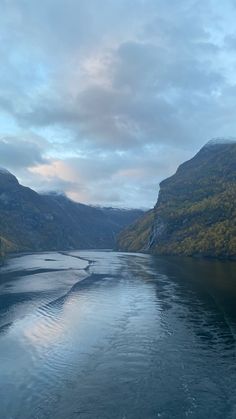 a boat traveling down a river surrounded by mountains