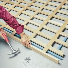 a man is working on the floor using a wrench and screwdriver to attach nails