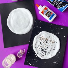 some crafting supplies are laying out on a purple surface with white and black paper