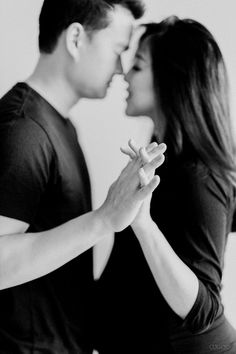 a man and woman kissing each other with their hands on the forehead while they are touching noses