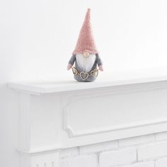 a gnome figurine sitting on top of a white mantle with a pink hat