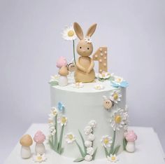 a cake decorated with flowers, mushrooms and a bunny sitting on top of the cake