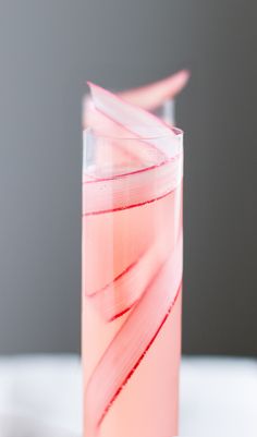 a tall glass filled with pink liquid on top of a table