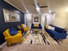 a living room with blue and yellow couches, white rugs and a ceiling fan