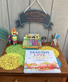 a table with books and toys on it next to a sign that says dragon's love