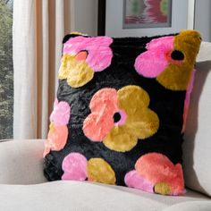 a black and pink pillow sitting on top of a white couch next to a window