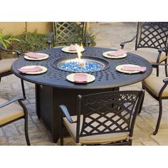 an outdoor table with chairs around it and a lit candle in the center surrounded by plates