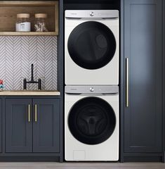 the front load washer and dryer combo are in this laundry room with gray cabinets