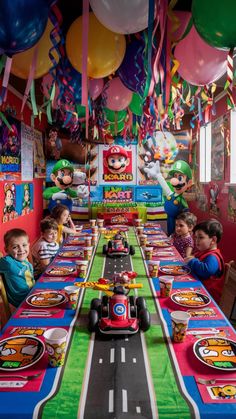 children sitting at a table with cars and balloons