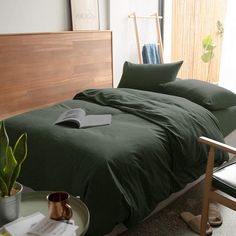 a bed sitting in a bedroom next to a green chair and table with a potted plant on it