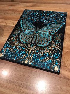 a blue and black butterfly painted on top of a wooden table with wood flooring