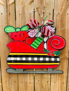 a wooden sign with a santa sleigh on it's side hanging on a fence