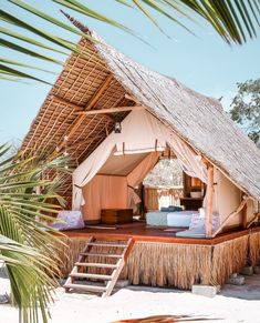 an outdoor tent set up on the beach with steps leading to it and a bed in the middle