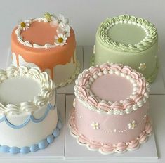 four different colored cakes sitting on top of a white countertop next to each other