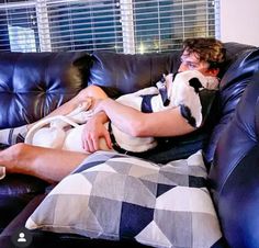 a man laying on top of a couch next to a dog