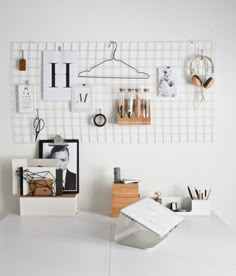 a white desk topped with lots of items on top of a wooden table next to a wall