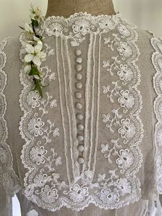 A very beautiful Edwardian blouse made from tulle and embroidered on the front and back bodice and on the hem of the sleeves. The front yoke is particularly stunning with 12 covered buttons adorning the centre front. The sleeves are slightly flared and have tucks above the embroidered hem. The body of the blouse is double layered and the under layer finishes with a small peplum at the hem which is created in sections. The blouse fastens down the back with poppers.  It fits my size 8 stand perfec Vintage Lace Blouses, Modesty Dress, Edwardian Blouse, Tulle Blouse, Breastfeeding Dress, Kaftan Designs, Embroidered Hem, Victorian Costume, Victorian Clothing