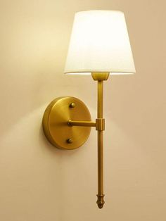 a wall mounted light with a white shade on it's side and a lamp attached to the wall