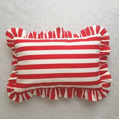 a red and white striped pillow with ruffled edges