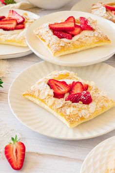 strawberry shortcakes on plates with powdered sugar and fresh strawberries in the background