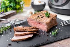 a piece of meat sitting on top of a cutting board next to a knife and fork