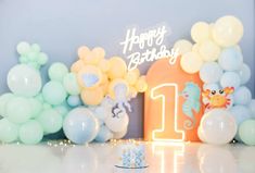 a birthday party with balloons and decorations on the table, including an ocean themed first birthday cake