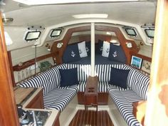 the interior of a sailboat with blue and white striped cushions, wooden flooring and wood trim