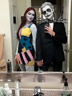 a man and woman dressed up in halloween costumes standing in front of a bathroom mirror