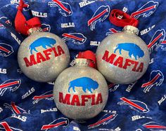 three ornaments with buffalo bills on them are sitting on a blue and red blanket in the shape of balls