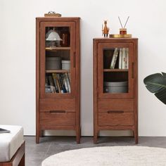 two wooden bookcases sitting next to each other in front of a white wall