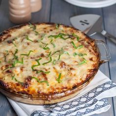 a pizza sitting on top of a wooden table next to plates and utensils