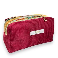 a red corded pouch with gold stars on the side and a name tag hanging from it