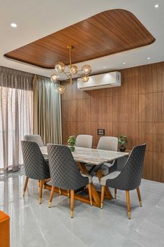 a dining room table with chairs and a chandelier hanging from the ceiling above it