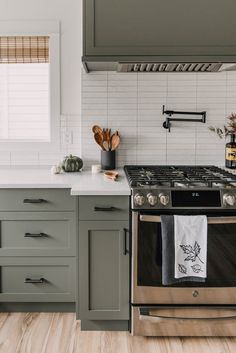 a stove top oven sitting inside of a kitchen next to a counter with utensils