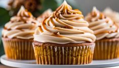 cupcakes with frosting and caramel drizzled on them sitting on a white plate