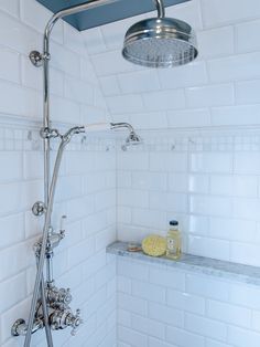 a shower head with thermostaer and faucet in white tiled bathroom