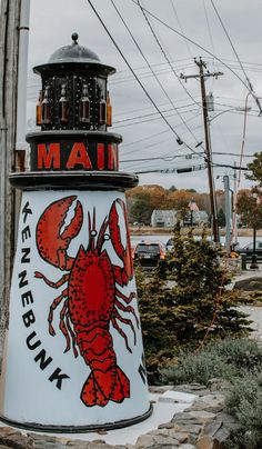 there is a sign that says maine with a lobster on it and a light house in the background