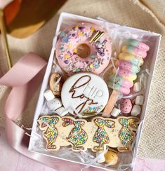 a box filled with lots of cookies and candies next to a pink satin ribbon