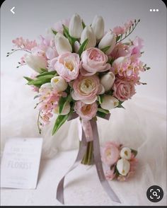 a bouquet of flowers sitting on top of a white table next to a card and envelope