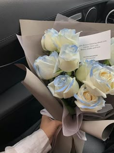 a bouquet of white roses sitting on top of a car dashboard