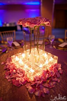 a centerpiece with flowers and candles on a table