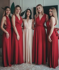 four women in long red dresses posing for a photo with one woman wearing a white dress