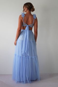 the back of a woman wearing a light blue dress with ruffles on it