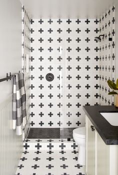 a bathroom with black and white tiles on the walls, flooring and shower curtain