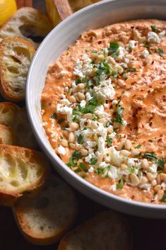 a white bowl filled with lots of food next to bread