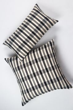 two black and white checkered pillows sitting on top of each other in front of a white background